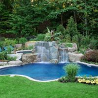 Stone waterfall on the shore of a garden pond