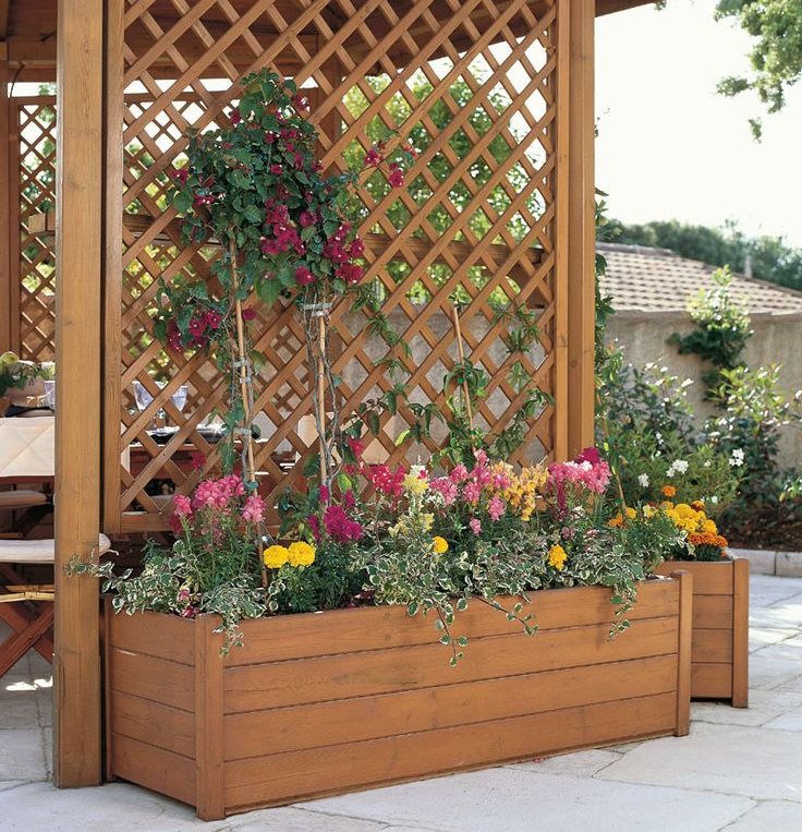 Box with flowers against the wall of a wooden arbor