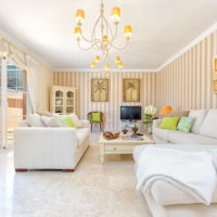 White furniture and bright stripes on the wallpaper in the living room