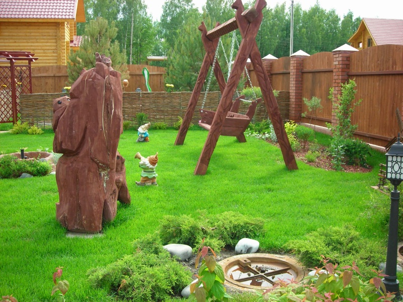 Wooden swing on the green lawn of a private garden