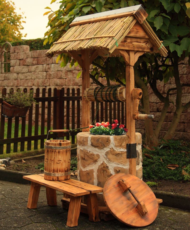 Small architectural form for the garden in the form of a decorative well made of stone and wood