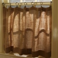 Window in living room of a country house with burlap curtain