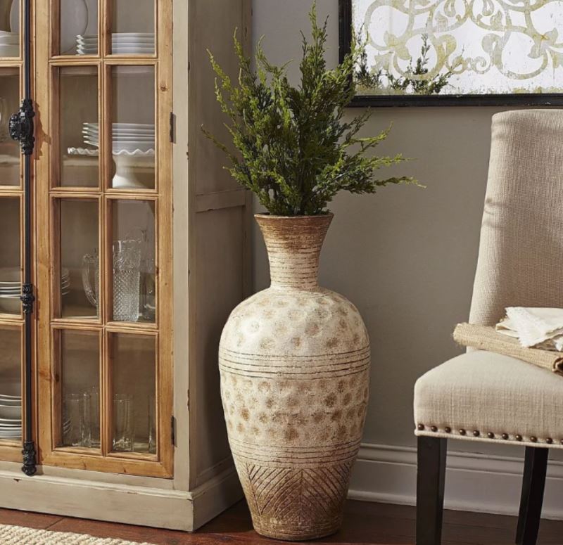 Classic vase with green branches on the living room floor