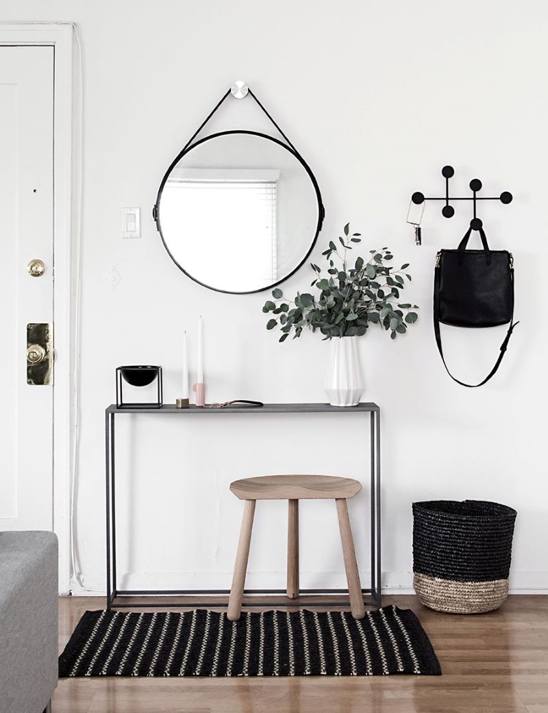 Round mirror in black frame on the white wall of the hallway