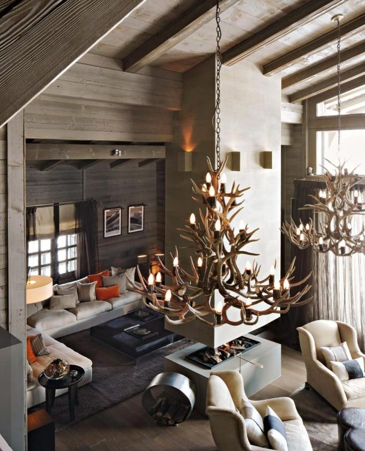 Huge chandeliers of deer horns on the ceiling of a living room in a wooden house