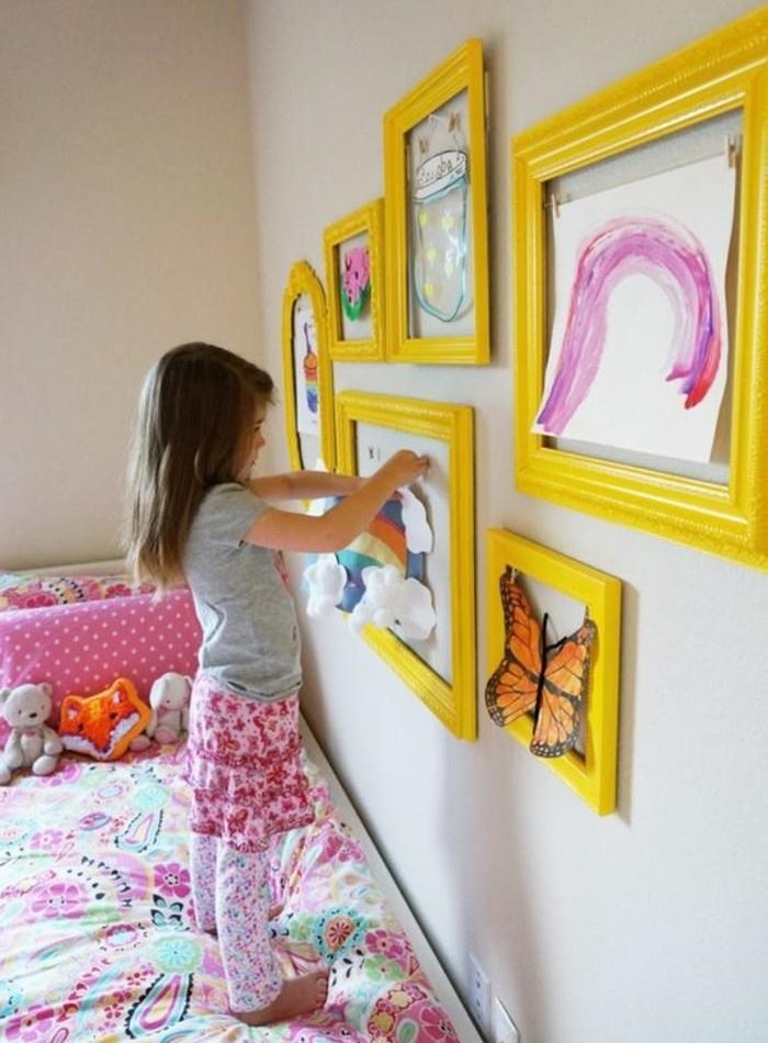 Girl decorates the room with her own drawings.