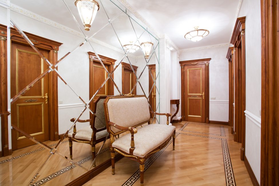 Brown doors in a narrow corridor with a mirror wall