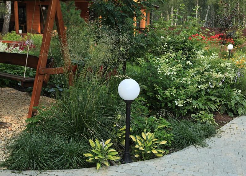 A small garden lantern in a flowerbed with hosts