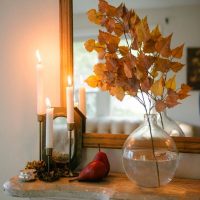 Twigs with dry birch leaves in a vase on a chest of drawers