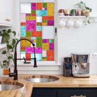 A small window with stained-glass windows above the kitchen sink