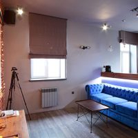 Roman curtains in the living room with a blue sofa