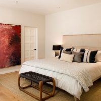 Designer pouf in front of a bed in a white bedroom