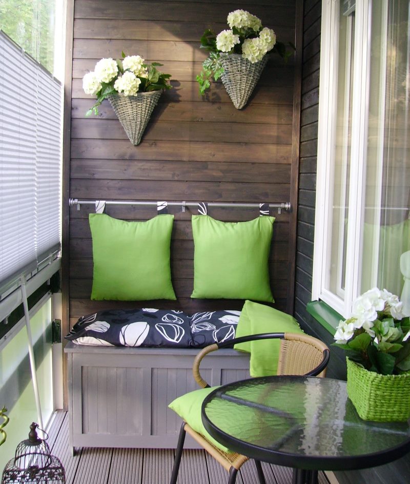 Planter with flowers on the wooden lining of the balcony