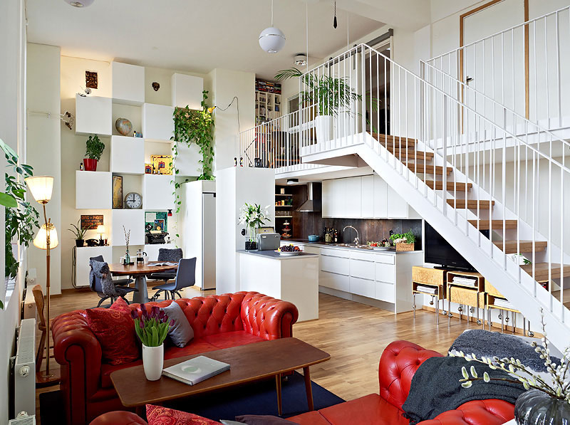 White staircase in the living room with red sofas.